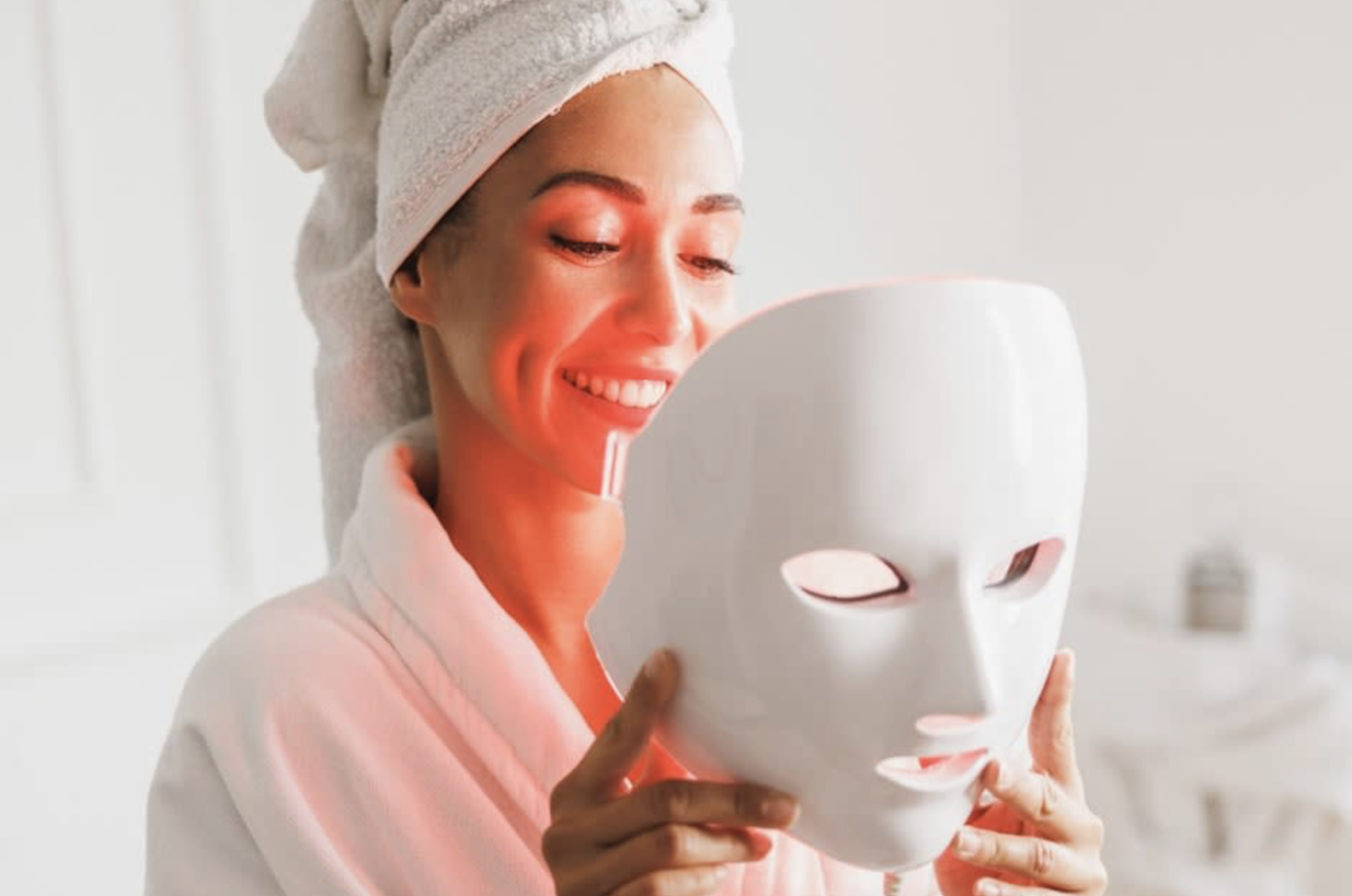 Woman smiling holding the LED mask after a session